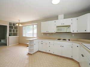 Kitchen with white appliances, white cabinetry, open shelves, a chandelier, and light countertops