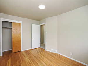 Unfurnished bedroom with light wood-style floors, baseboards, and a closet