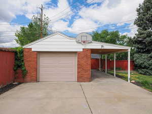 Garage with fence, driveway, and a detached garage