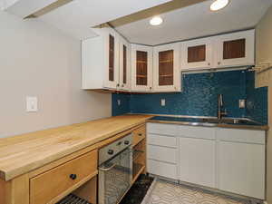 Kitchen with butcher block counters, a sink, recessed lighting, decorative backsplash, and white cabinets