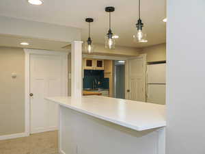 Kitchen with freestanding refrigerator, a sink, a peninsula, recessed lighting, and hanging light fixtures