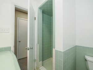 Bathroom with a shower stall, toilet, and tile patterned floors
