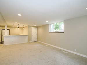 Unfurnished living room with recessed lighting, light carpet, and baseboards