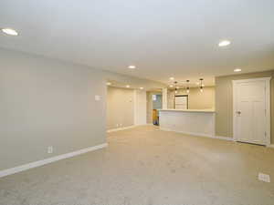 Unfurnished living room featuring recessed lighting, light carpet, and baseboards