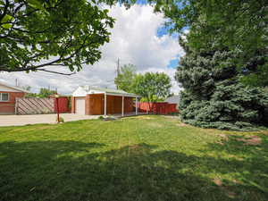 View of yard featuring concrete driveway, an outdoor structure, and an attached garage