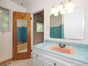 Full bath with vanity, washtub / shower combination, tile patterned floors, and baseboards