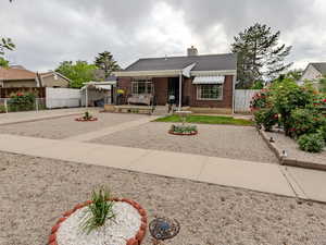 View of front of home featuring brick siding, fence, and a chimney