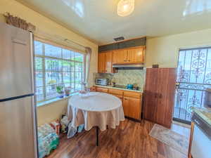 Kitchen featuring freestanding refrigerator, wood finished floors, white dishwasher, decorative backsplash, and light countertops