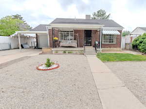 Bungalow featuring fence, brick siding, driveway, and an attached carport