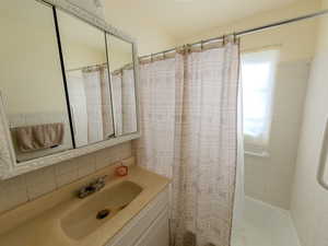 Bathroom featuring shower / bath combo with shower curtain and vanity