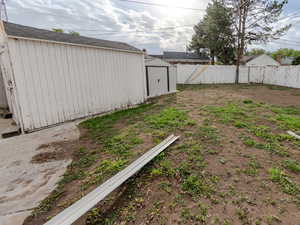 Fenced backyard featuring a shed and an outdoor structure
