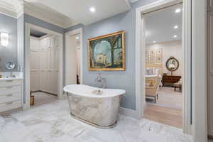 Full bath featuring crown molding, a soaking tub, marble finish flooring, recessed lighting, and vanity