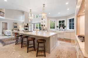 Kitchen featuring stainless steel gas stovetop, recessed lighting, white cabinets, ornamental molding, and light stone counters