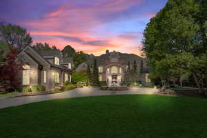 French country style house featuring a front lawn, curved driveway, and stone siding