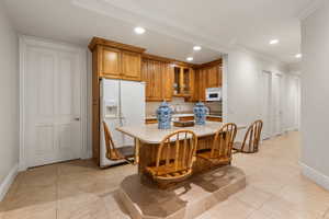 Kitchen with white appliances, brown cabinets, light countertops, recessed lighting, and baseboards