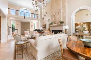 Living area with a towering ceiling, a chandelier, arched walkways, ornamental molding, and stairs