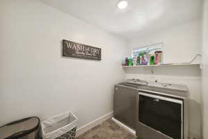 Clothes washing area featuring separate washer and dryer and baseboards