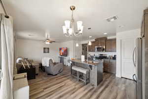 Kitchen featuring stainless steel appliances, open floor plan, a breakfast bar area, a sink, and wood finished floors