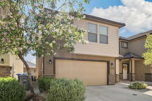 Multi unit property with stucco siding, an attached garage, driveway, stone siding, and central AC unit