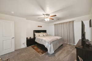 Carpeted bedroom with ceiling fan and baseboards