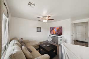 Living area with ceiling fan and baseboards
