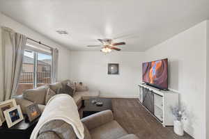 Living room featuring ceiling fan, dark carpet, and baseboards