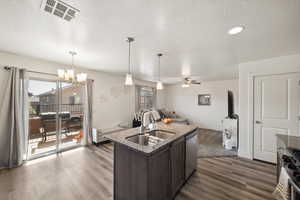 Kitchen with a sink, stainless steel appliances, dark brown cabinetry, dark wood-style flooring, and dark stone counters