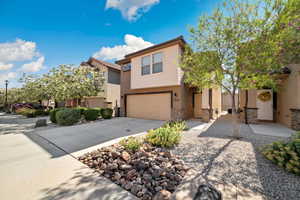 View of front of property featuring a garage, stone siding, driveway, and stucco siding
