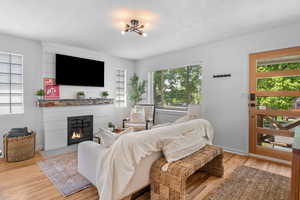 Living area featuring a fireplace with flush hearth, light wood-type flooring, and baseboards