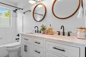 Full bathroom featuring double vanity, toilet, and shower / bath combo with shower curtain