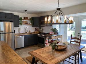 Kitchen featuring stainless steel appliances, a sink, butcher block countertops, and decorative backsplash