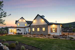 Back of property featuring a yard, a patio, stone siding, and a chimney