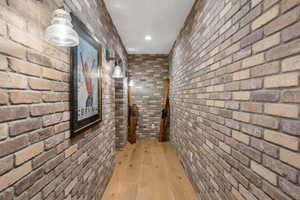 Corridor with brick wall and light wood-style flooring