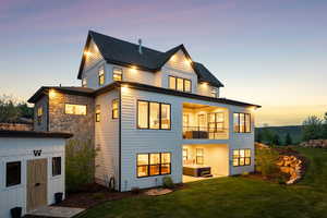 Rear view of property with a lawn, a balcony, an outdoor structure, and a storage unit