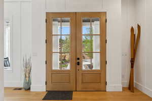 Doorway to outside featuring light wood-type flooring, french doors, and baseboards