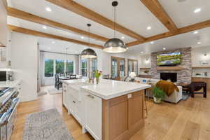 Kitchen featuring a sink, recessed lighting, light wood-style flooring, beamed ceiling, and double oven range