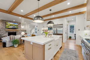 Kitchen featuring high end appliances, recessed lighting, light wood-style floors, beam ceiling, and tasteful backsplash