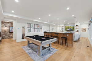 Rec room with billiards table, recessed lighting, light wood finished floors, brick wall, and bar with sink