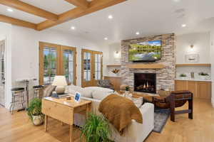 Living room featuring french doors, light wood finished floors, recessed lighting, a brick fireplace, and beam ceiling