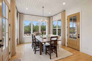 Dining space with a chandelier, light wood-style floors, plenty of natural light, recessed lighting, and wooden ceiling