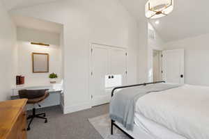 Carpeted bedroom featuring high vaulted ceiling, baseboards, a desk, and a closet