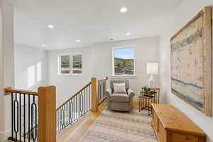 Sitting room with healthy amount of natural light, an upstairs landing, recessed lighting, and light wood-style flooring