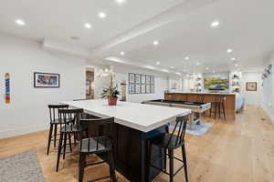 Kitchen with a large island, recessed lighting, baseboards, light wood-type flooring, and light countertops