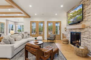 Living area with wood finished floors, recessed lighting, a fireplace, french doors, and a wainscoted wall