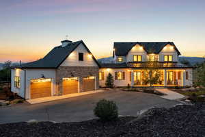 View of front of property with covered porch, concrete driveway, stone siding, an attached garage, and a chimney
