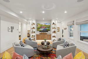 Living room with light wood-style floors, baseboards, recessed lighting, and built in shelves