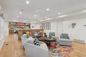 Living room featuring light wood-style floors, recessed lighting, and bar area