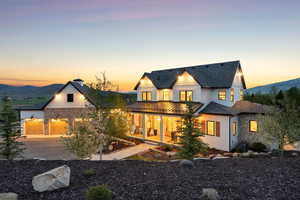 Back of property at dusk with covered porch, driveway, central AC unit, an attached garage, and a mountain view