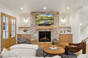 Living area featuring wood finished floors, french doors, recessed lighting, built in shelves, and a fireplace
