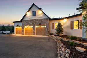 View of front of house with stone siding, driveway, and a garage